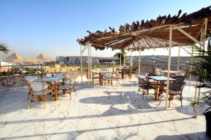 patio con tavoli e sedie sotto un ombrellone di paglia di Topview Pyramids And Museum a Il Cairo
