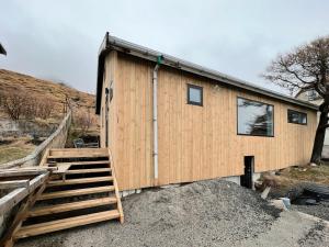a wooden house with a staircase leading to it at Stunning 3 Bedroom Family Friendly Retreat in Tvøroyri