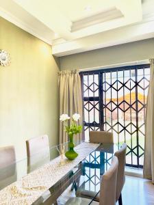 a dining room with a glass table and a large window at Townhouse on 6526 Boiketlo Street, Golfview in Mahikeng