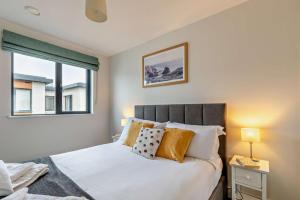 Un dormitorio con una cama con almohadas y una ventana. en 12 Putsborough - Luxury Apartment at Byron Woolacombe, only 4 minute walk to Woolacombe Beach!, en Woolacombe 36 fotos más