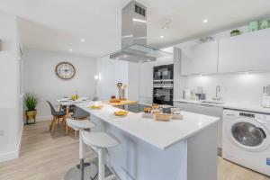 a white kitchen with a washer and dryer at 6 Putsborough - Luxury Apartment at Byron Woolacombe, only 4 minute walk to Woolacombe Beach! in Woolacombe