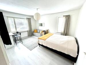 a white bedroom with a bed and a desk at Yksiö ilmaisella autopaikalla in Jyväskylä