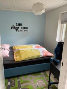 um quarto com uma cama e uma placa de sala de jogos na parede em Nice and Cozy family house at Billund Center em Billund