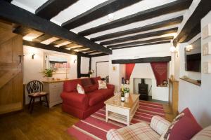 uma sala de estar com um sofá vermelho e uma mesa em Daisy Cottage em Warwick