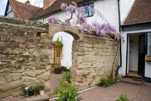 un edificio con una pared de piedra con flores púrpuras. en Daisy Cottage, en Warwick