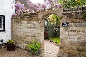 un arco en una pared de piedra con flores púrpuras en Daisy Cottage en Warwick