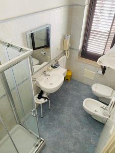 un bagno con lavandino, water e specchio di Albergo Bouganville a Favignana