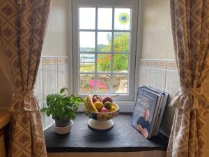a bowl of fruit on a window sill with a book at Banc Cottage in Pembrokeshire +9 photos