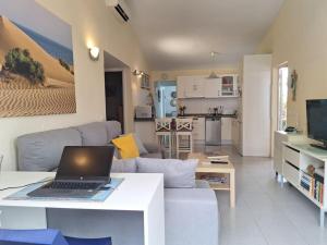 a living room with a couch and a laptop on a table at Oasis Los Porches in Playa del Ingles