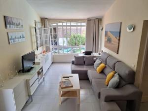 a living room with a couch and a tv at Oasis Los Porches in Playa del Ingles