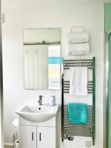 a bathroom with a sink and a mirror and towels at Hightide in Bude