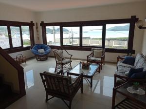 a living room with chairs and a table and windows at Pousada Canto da Baleia in Arraial do Cabo