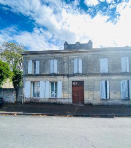 un vecchio edificio in mattoni con una porta rossa su una strada di Le nid des Petits à 15 min de Bordeaux a Sainte-Eulalie