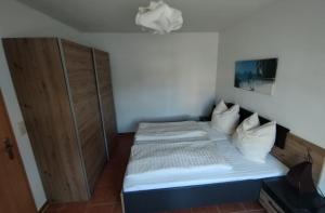 a small bedroom with a bed and a wooden cabinet at Ferienhaus Am Stadtpark in Ballenstedt