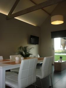 a dining room with a table and white chairs at Hoveke Paddebroek in Alveringem