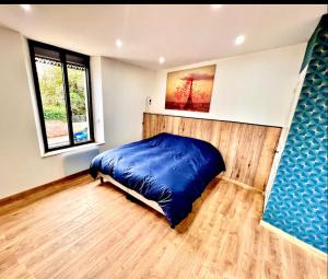 a bedroom with a blue bed and a window at La Maison du faubourg & Spa in Vitry-le-François