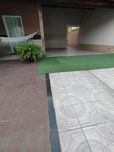a patio with a green floor and a hammock at Casa na Praia in Jacaraípe