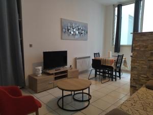 a living room with a television and a table with chairs at Chalet Elaïa in Eaux-Bonnes