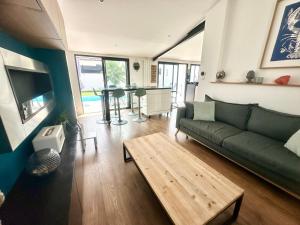a living room with a green couch and a table at La Romerel/Maison piscine/400m plage et commerces! in Châtelaillon-Plage