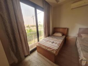 Un dormitorio con una cama y una ventana grande en Shared City Stay at Midtown Compound next to the AUC University, en El Cairo 17 fotos más