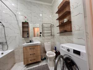 a white bathroom with a washing machine in it at Апартаменты с видом на море в центре in Aktau +6 photos