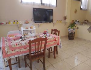 a dining room with a table and chairs and a tv at Carpe Diem da Salvina in Pachino