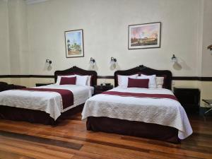 a bedroom with two beds with red and white sheets at Hotel Santo Tomás in San José