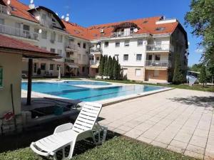 une chaise blanche assise à côté d'une piscine dans l'établissement Studio N2 Apartman, à Hajdúszoboszló