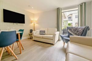 sala de estar con sofá, silla y TV en 4 Woolacombe West - Luxury Apartment at Byron Woolacombe, only 4 minute walk to Woolacombe Beach!, en Woolacombe