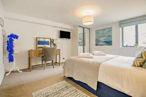 Un dormitorio con dos camas y un escritorio y un espejo. en 4 Woolacombe West - Luxury Apartment at Byron Woolacombe, only 4 minute walk to Woolacombe Beach!, en Woolacombe 27 fotos más