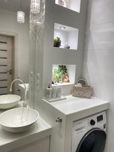 a white bathroom with a sink and a washing machine at Apartament Dani-Apart in Gdańsk +62 photos