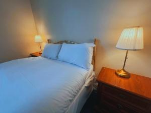 a bedroom with a bed and a table with a lamp at Helen's Hotel near Wembley in London