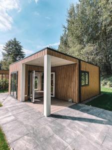 a small house with a large patio in a yard at Tiny House Cinta- Dichtbij zee & in een groene omgeving in Heinkensand