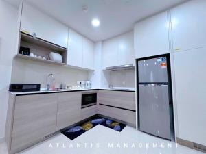 a kitchen with white cabinets and a refrigerator at Midvally Mega Mall, Link With The Garden, KL ECO City By Atlantis Management in Kuala Lumpur