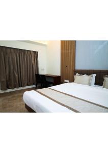 a hotel room with a large bed and a desk at Nisarg Resort in Guhagar