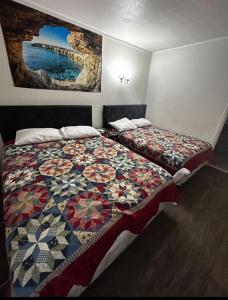 a bedroom with two beds with a quilt on it at Anchor Motel & RV Park in Surfside Beach