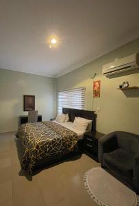 a bedroom with a bed and a couch and a chair at Vintage Homes Lekki in Lagos