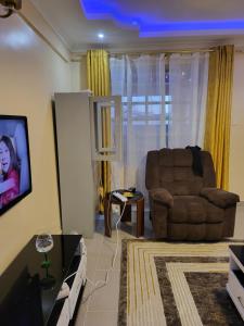 a living room with a chair and a tv at G&G Homes Pioneer 2 Bedroom in Eldoret