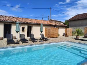 a swimming pool in front of a house with chairs and umbrellas at Maison Juliette in Loupiac-de-Cadillac