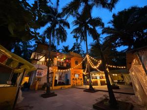 a building with christmas lights and palm trees at night at Mandala House - Party hostel in Palolem