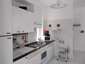 a white kitchen with a stove and a sink at Casa Re di Picche in San Nicola Arcella
