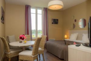 a hotel room with a bed and a table and chairs at Résidence de Tourisme Vacances Bleues Villa Regina in Arcachon