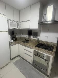 a kitchen with white cabinets and a stove top oven at Ed forte da Praia in Guarapari