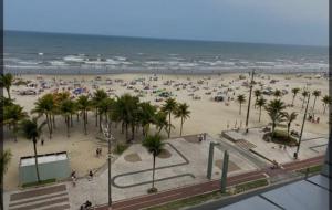 a beach with a lot of people and the ocean at Apartamento com varanda in Samaritá