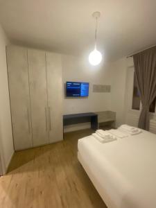 ein Schlafzimmer mit einem weißen Bett und einem Fernseher in der Unterkunft SUITE grassi in Bresso