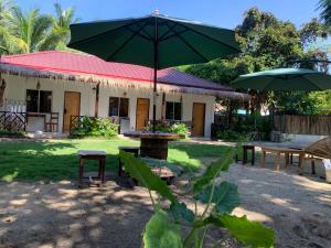 a patio with a table and a green umbrella at Bakoko Garden in El Nido