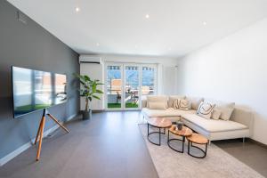 ein Wohnzimmer mit einem weißen Sofa und einem Fernseher in der Unterkunft Renovated Lake View Apt with AirCon in Minusio