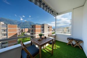 ein Balkon mit Tisch und Stühlen und einem großen Fenster in der Unterkunft Renovated Lake View Apt with AirCon in Minusio