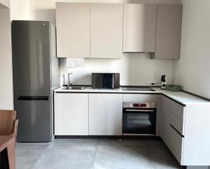a kitchen with white cabinets and a stainless steel refrigerator at STADLERINO - Tiny Loft in Venice in Marghera