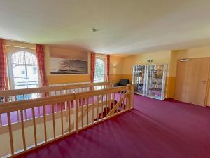 an empty room with purple carpet and a balcony at Hotel Strandburg Prerow in Prerow